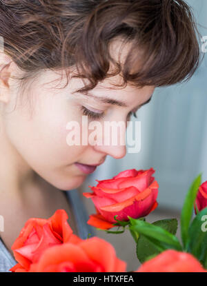 Frau riechen rote Rosen Blumenstrauß in der Vase im Profil Stockfoto