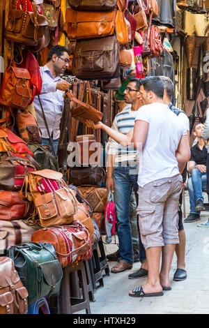 Fes, Marokko.  Straßenszene in der Medina.  Männer diskutieren Verkauf eine Ledertasche. Stockfoto
