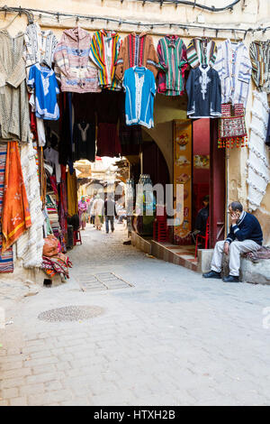 Fes, Marokko.  Straßenszene in der Medina.  Kleidung zu verkaufen. Stockfoto