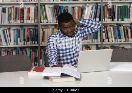 Betonte afrikanische Schüler der High School am Bibliothek Schreibtisch - geringe Schärfentiefe Stockfoto