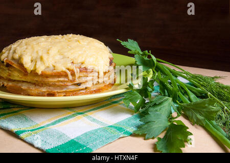 Pfannkuchen Sie-Torte mit Champignons und Hühnerfleisch, überbacken mit Käse auf grüne Platte. Pfannkuchen-Kuchen auf Teller mit Kräutern grün: grüne Zwiebel, Dill, Petersilie Arou Stockfoto