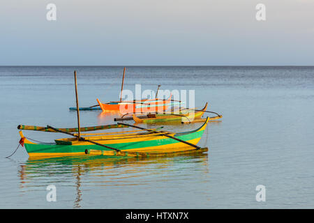 Drei traditionelle Filiopino Fishermans Boote mit Ausleger friedlich in einem noch ruhigen Meer schweben. Stockfoto