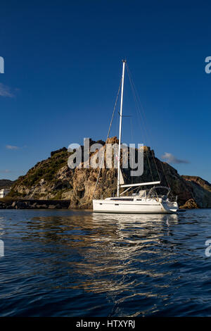 Segelboot, Yacht auf einem Meeresfelsen, kleine vulkanische Insel. Mittelmeer, Äolische Inseln. Sizilien, Italien. Stockfoto