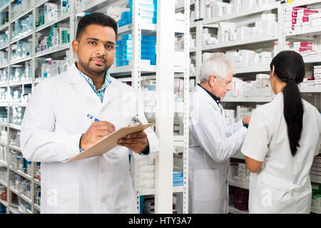 Zuversichtlich Chemiker schreiben in Zwischenablage während Kollegen stehen Stockfoto