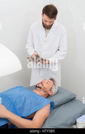 Arzt schriftlich in Zwischenablage beim Mann durchläuft Knochen Densitomet Stockfoto