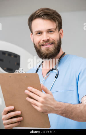 Junge männliche Radiologe hält Zwischenablage im Untersuchungsraum Stockfoto