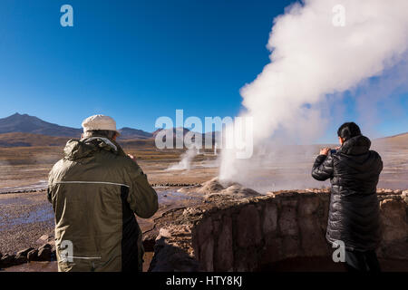 Geysire del Tatio, Chile - 24. November 2013: Touristen beobachten einen Geysir im Feld del Tatio Geysire in der Atacama-Wüste in Nordchile Stockfoto