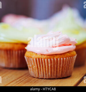 Dessert süße Gourmet Cupcakes mit bunten Zuckerguss auf hölzernen Hintergrund Stockfoto
