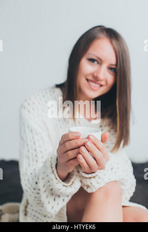 Frau in Strickpullover mit einer Tasse Kaffee sitzen Stockfoto
