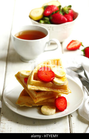 Tee und Waffeln mit Erdbeeren, Banane und Ahornsirup Stockfoto