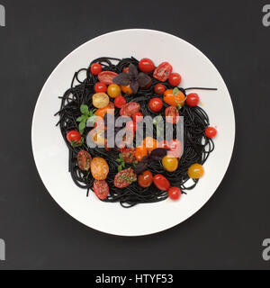Schwarzen Tintenfisch Tinte Pasta mit frischen Tomaten und Basilikum Stockfoto