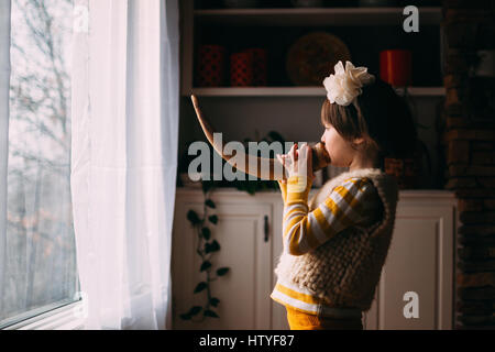 Mädchen stehen vor Fenster weht ein horn Stockfoto