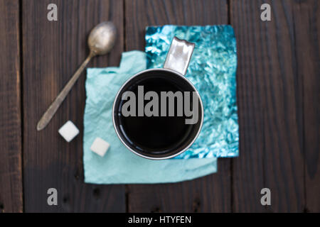 Eine Tasse Kaffee an Ständen gemacht farbige Folie auf einer Holzoberfläche Stockfoto