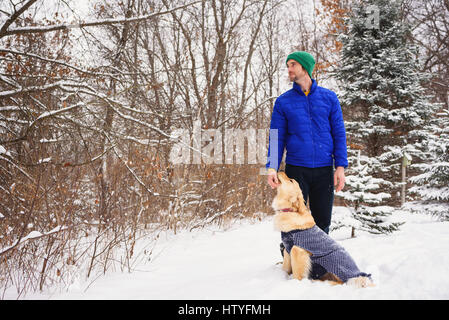 Mann streicheln golden Retriever Hund draußen im Schnee Stockfoto