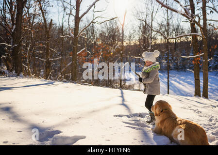 Mädchen spielen im Schnee mit golden Retriever Hund Stockfoto