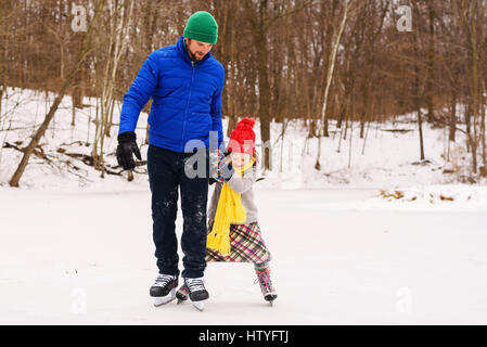 Vater und Tochter Schlittschuhlaufen auf zugefrorenen Teich Stockfoto