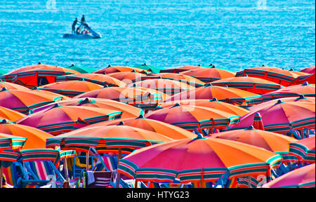 Sonnenschirme am Strand mit einem Boot in der Ferne, Italien Stockfoto