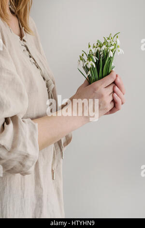 Bouquet von wilden Schneeglöckchen in Famale Händen. Frau in weißem Leinen Kleid. Tageslicht. Frühling Geschenk. Stockfoto