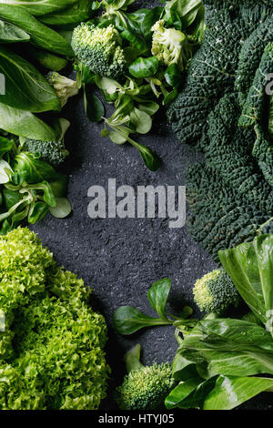 Vielzahl von rohem Gemüse Salate, Salat, Chinakohl, Mais, Brokkoli, Wirsing als Frame über schwarze Steinstruktur Hintergrund. Ansicht von oben, Raum Stockfoto