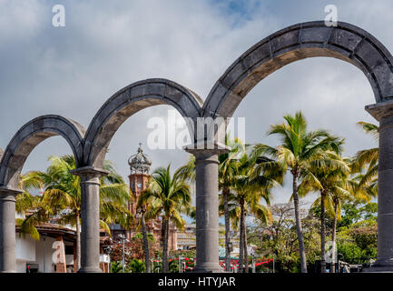 Blick auf Puerto Vallarta durch die Bögen oder Los Arcos auf dem Malecon zeigt Altstadt oder Old Vallarta und Our Lady of Guadalupe Church Tower. Stockfoto