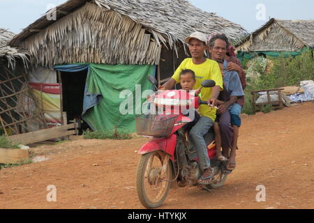 Familie auf Motorrad in einem Macadam schmutzige Straße in einem Dorf, Siem Reap, Kambodscha. Stockfoto