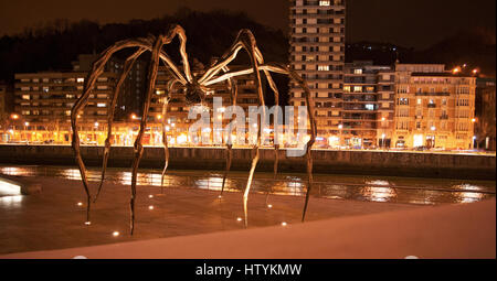 Bilbao: Maman, die Riesenspinne Skulptur von Louise Bourgeois an der Außenseite des Guggenheim Museum Bilbao mit Blick auf die Skyline der Nacht Stockfoto