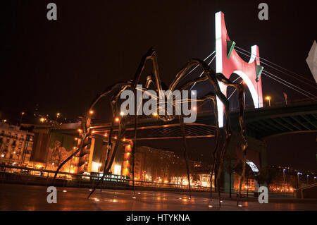 Bilbao: Maman, die Riesenspinne Skulptur von Louise Bourgeois an der Außenseite des Guggenheim Museum Bilbao mit Blick auf die Skyline der Nacht Stockfoto