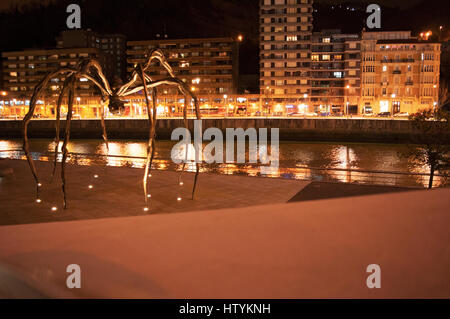 Bilbao: Maman, die Riesenspinne Skulptur von Louise Bourgeois an der Außenseite des Guggenheim Museum Bilbao mit Blick auf die Skyline der Nacht Stockfoto