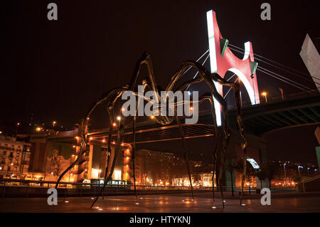 Bilbao: Maman, die Riesenspinne Skulptur von Louise Bourgeois an der Außenseite des Guggenheim Museum Bilbao mit Blick auf die Skyline der Nacht Stockfoto