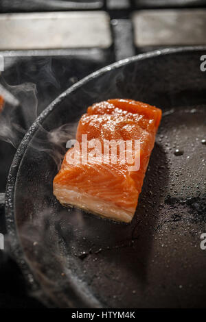Braten von Lachs in schwarze Pfanne in Restaurantküche Stockfoto