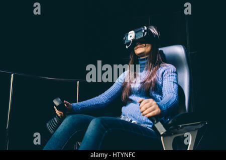 Junge schöne östlichen Frau sitzen auf einer Gaming-Stuhl testen erweiterten Realität mit 3D Viewer - Spiele, futuristisch, augmented Reality-Konzept Stockfoto