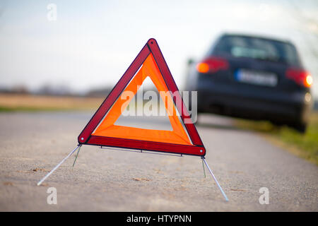 Pannendreieck steht in der Nähe ein kaputtes Auto Stockfoto