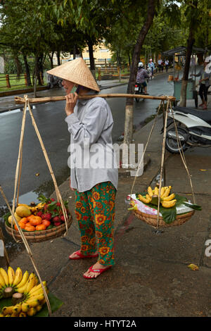Vietnamesische Frau, die die Produkte auf einem Bambus-Joch, Hoi an ein (UNESCO Weltkulturerbe), Vietnam Stockfoto