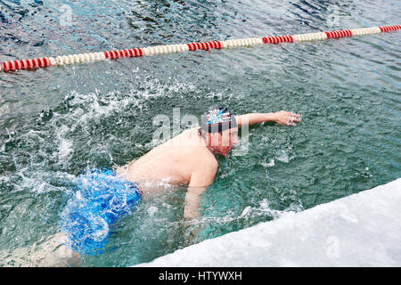 SAHYURTA, Gebiet IRKUTSK, Russland - März 11.2017: Cup des Baikalsees. Winter-Schwimmwettkampf. Ein Mann schwimmt mit einem Freestyle in sehr kaltem Wasser Stockfoto