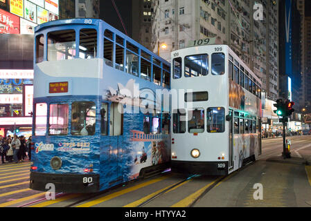 2 Straßenbahnen überqueren einer verkehrsreichen Kreuzung für Fußgänger über die Straße mit Neonröhren in Causeway Bay, blur Hong Kong Island, mit einigen Motion. Stockfoto
