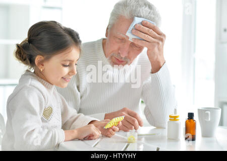 Enkelin kümmert sich um einen kranken Großvater Stockfoto