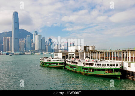 Die Star Ferry Pier in Tsim Sha Tsui mit 2 Fähren bereit zu gehen und die Wolkenkratzer von Hong Kong Island und die IFC-Gebäude hinter. Stockfoto
