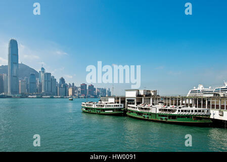 Die Star Ferry Pier in Tsim Sha Tsui mit 2 Fähren bereit zu gehen und die Wolkenkratzer von Hong Kong Island und die IFC-Gebäude hinter. Stockfoto