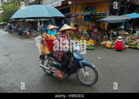 Vietnamesische Frau mit Regenschirm auf dem Motorrad, Hoi an ein (UNESCO Weltkulturerbe), Vietnam Stockfoto
