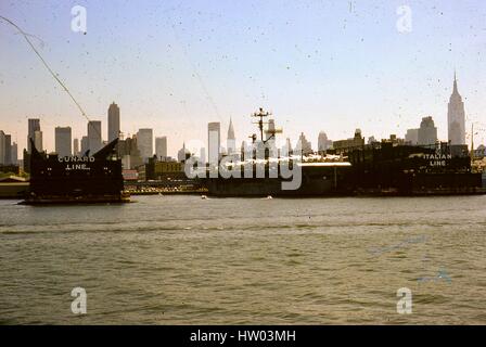 Blick vom Hudson River von der Cunard Line und italienischen Line Pfeiler auf der New York City Passenger Ship Terminal, bekannt als Luxus-Liner Row, im Stadtteil "Hells Kitchen" auf der Westseite von Manhattan, New York City, New York, August 1966. Im Vordergrund zu sehen ist ein Kreuzfahrtschiff Italia Pier 88 angedockt während Cunard 50th Street Pier 90 leer ist. Wahrzeichen Wolkenkratzer im Hintergrund zu sehen sind das GE Building am Rockefeller Center, Pan bin Building, das Chrysler Building und das Empire State Building. Stockfoto