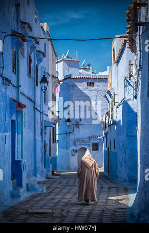 Mann mit einem traditionellen Kleid ist in der blauen Medina von Chefchaouen, Marokko Fuß. Stockfoto