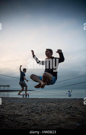 Aberystwyth Wales Uk, Mittwoch, 15. März 2017 UK Wetter: Aberystwyth Universitätsstudenten üben ihre Slack-Line Wandern und Ausgleich Fähigkeiten am Strand in der Abenddämmerung als der graue Regen Wolken Roll in über Cardigan Bay Wales UK Foto Credit: Keith Morris Alamy Live News Stockfoto