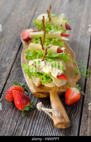 Kanapees mit leckeren Käsebrötchen und Erdbeeren auf italienische Ciabatta Brot mit Salatblättern Stockfoto