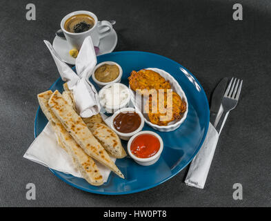 Orientalisch-indischen festgelegt, Naan Brot und Zwiebel Bhaji, vier Saucen, blaue Platte, schwarzer Kaffee, leckere Satz Stockfoto