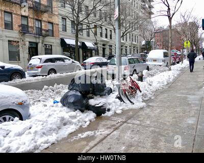 NYC-Straße nach Sturm Stella. Fußgänger und Autos navigieren Schneematsch, Müll und Haufen von schmutzigem Schnee. Upper Eastside, New York City, NY, USA Stockfoto