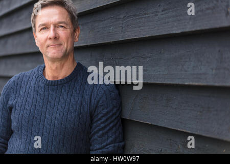 Porträt gedreht von einem attraktiven, erfolgreichen und glücklichen Mann mittleren Alters männlichen außerhalb trägt einen blauen Pullover Stockfoto