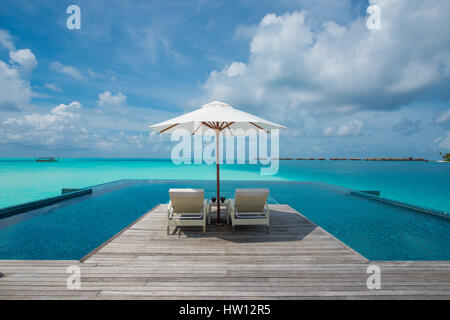 Maldives Rangali Island. Conrad Hilton Resort. Liegestühle und Sonnenschirm am Pool in der Nähe des Ozeans. Stockfoto
