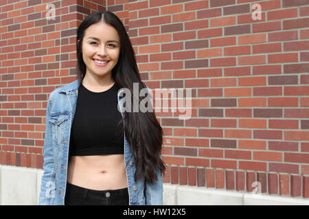 Schöne Frau, lächelnd und stehen gegen eine Mauer. Stockfoto