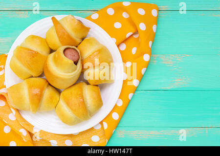 Frisch gebackene kleine Brötchen auf einem weißen Teller. Würstchen im Teig. Die Ansicht von oben Stockfoto