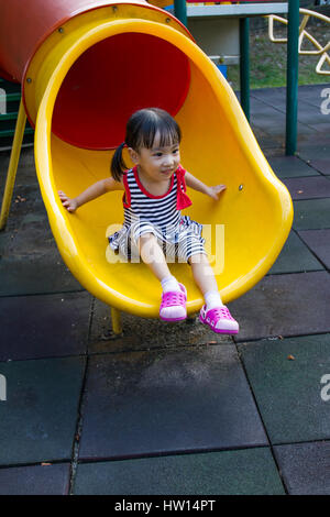 Asiatische chinesische Mädchen gleiten auf Spielplatz im Freien. Stockfoto